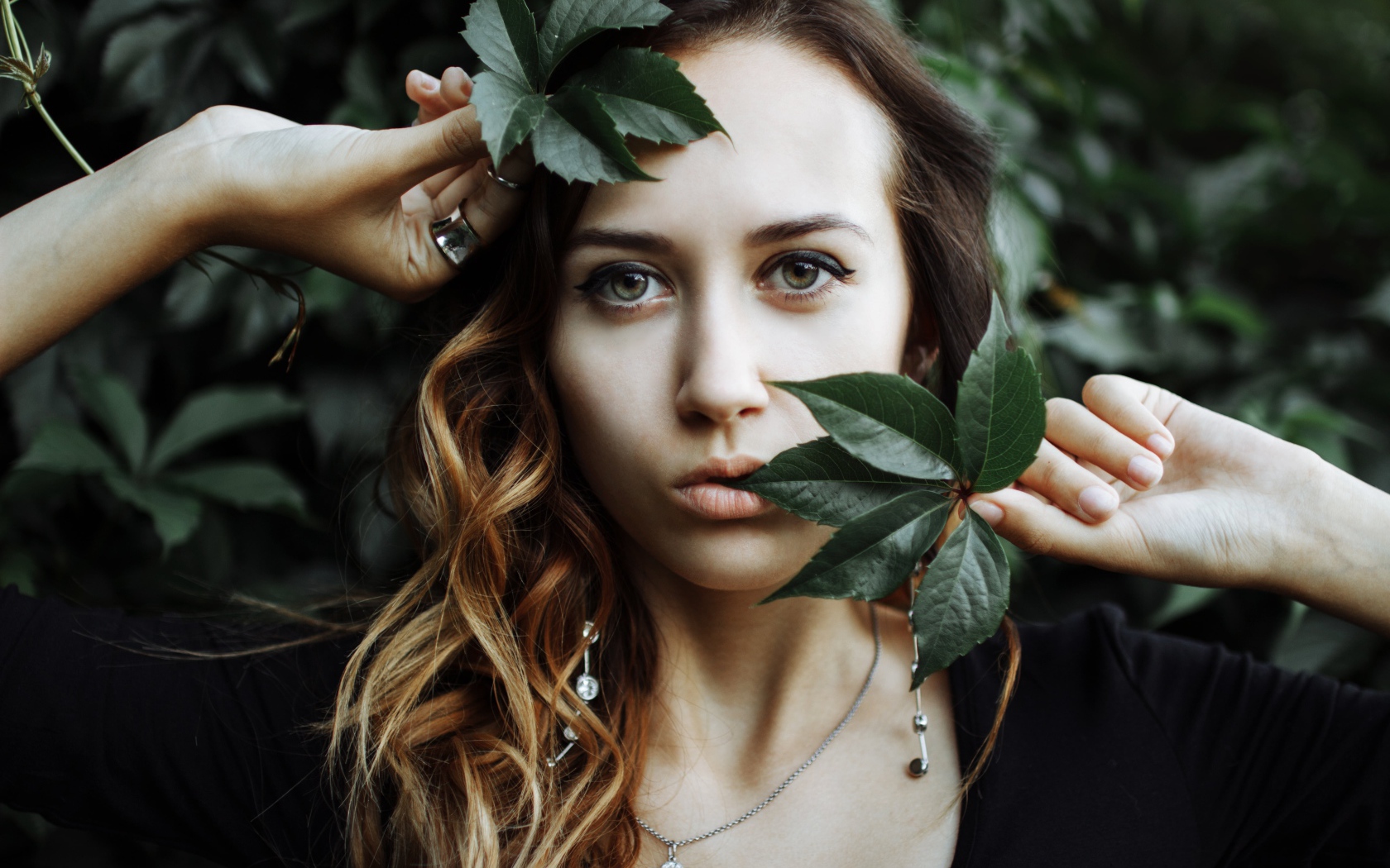 Молодая девушка с зелеными листьями в руках 
