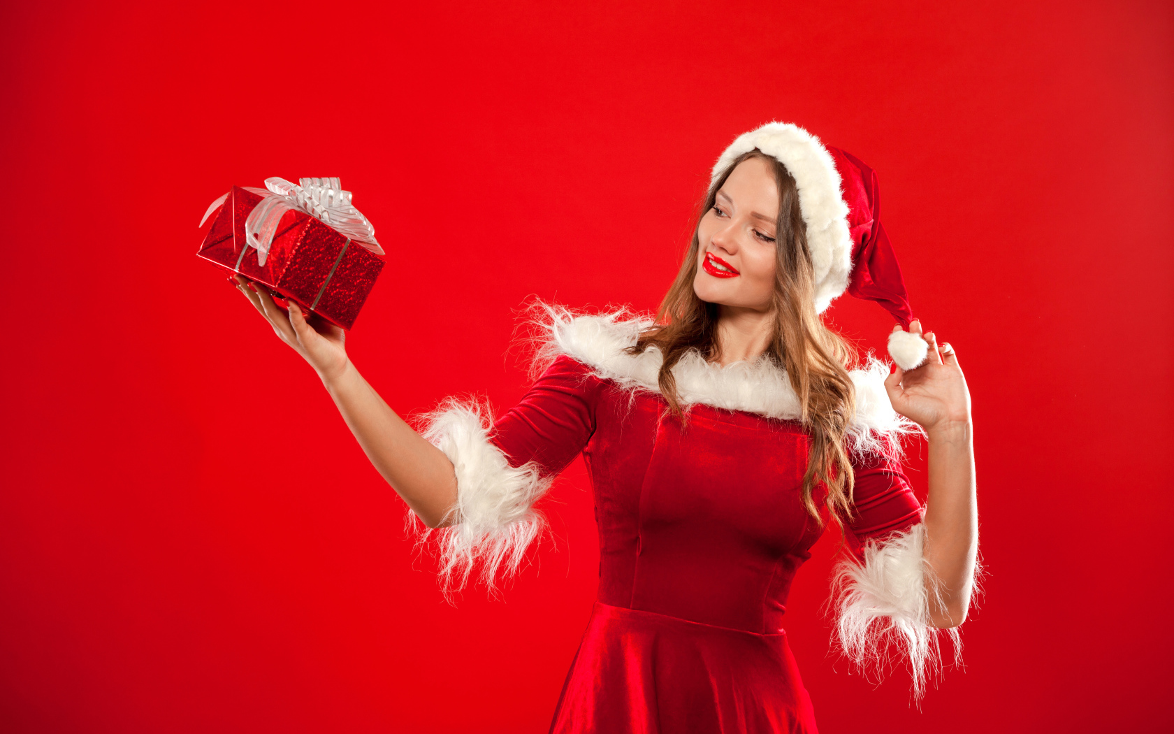 Красивая Снегурочка с подарком в руке на красном фоне