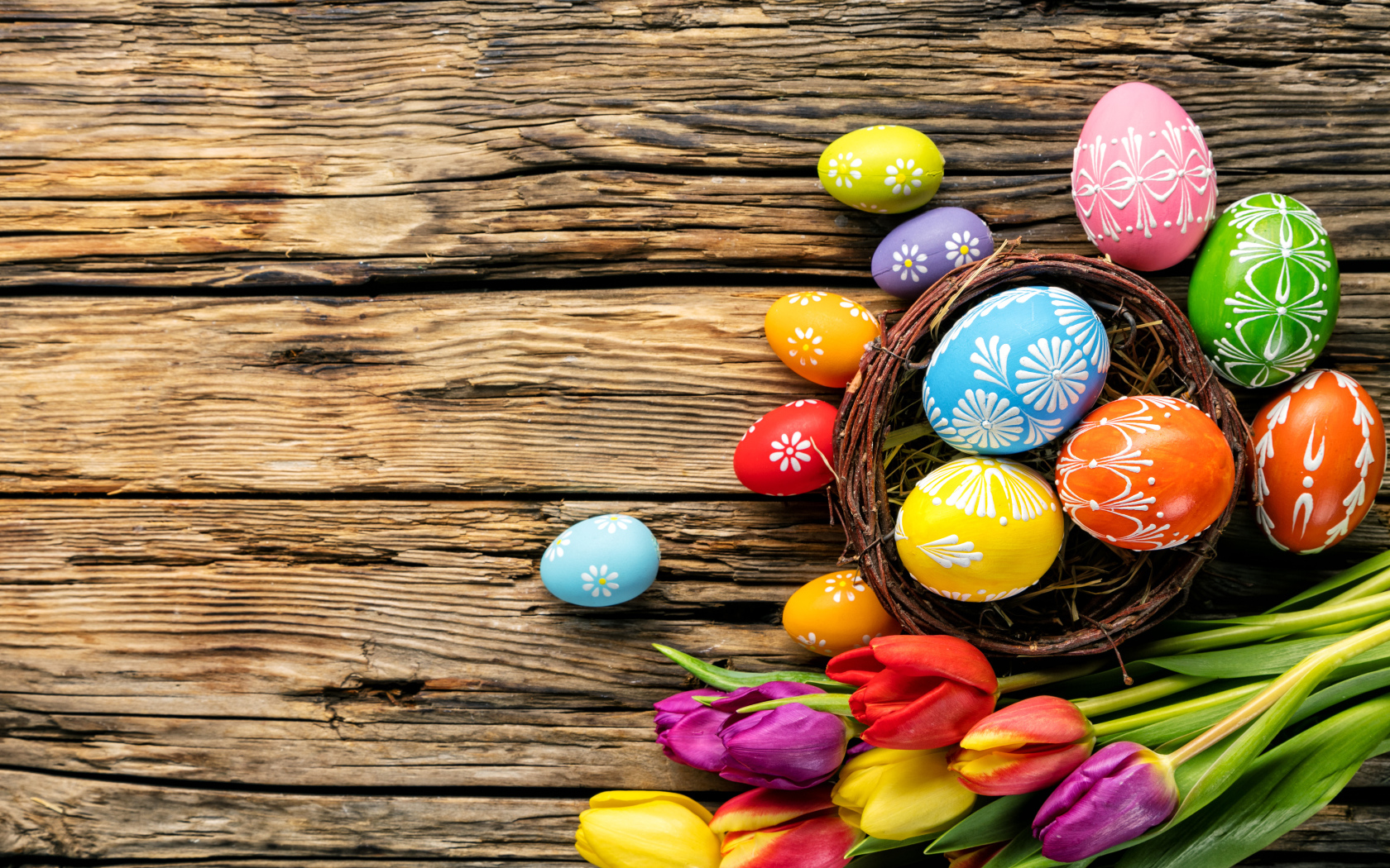 Крашеные пасхальные яйца с букетом тюльпанов на деревянном фоне