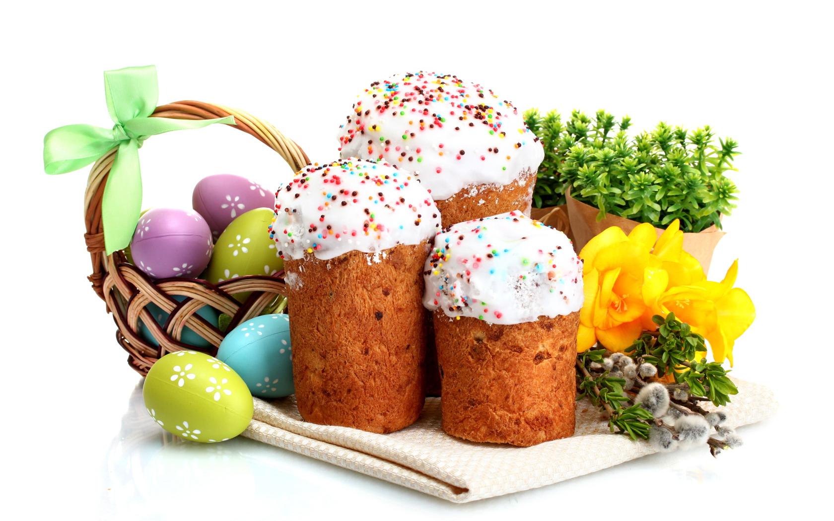 Three sweet cakes on white background with flowers and painted eggs for the holiday Easter