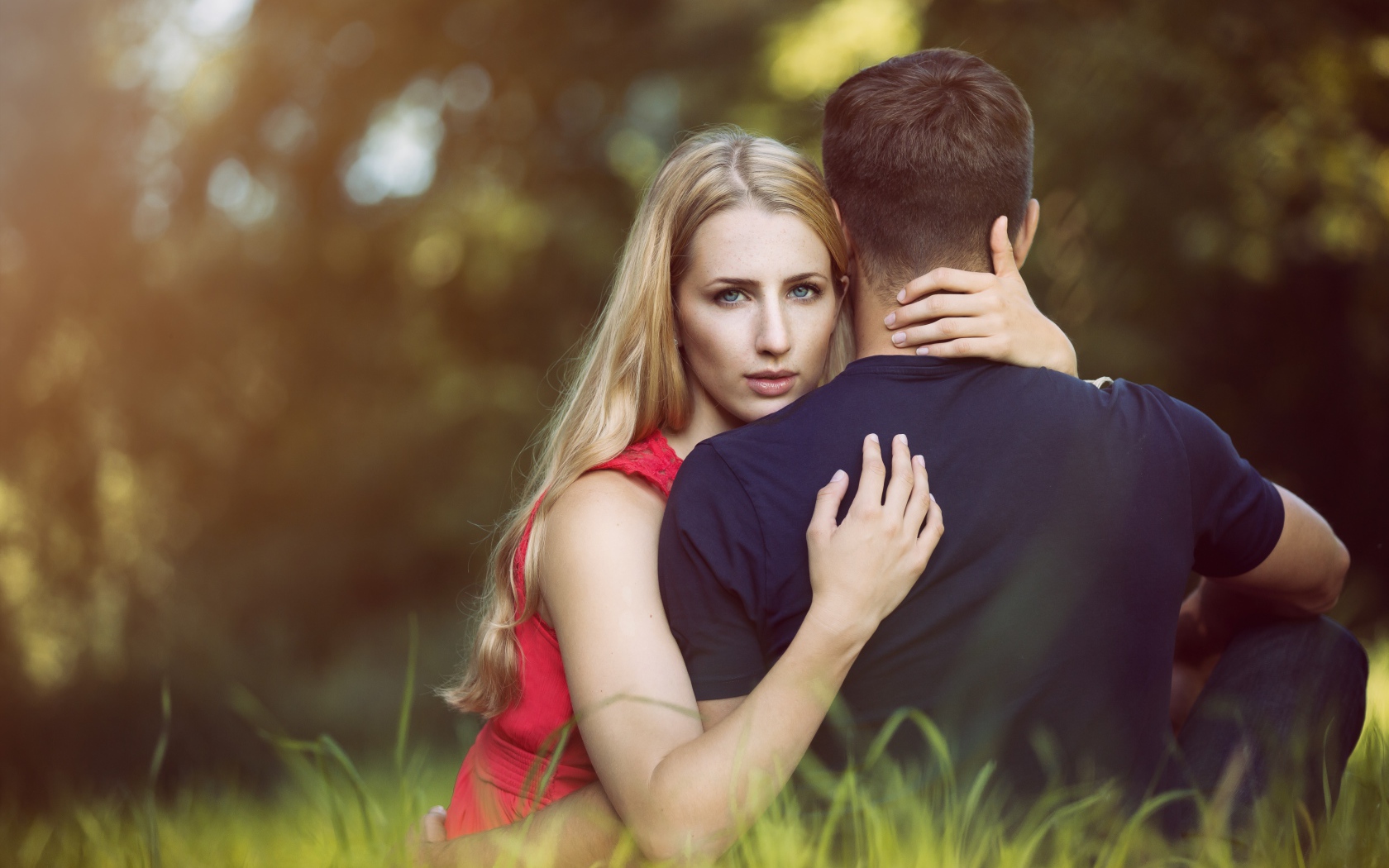 Красивая девушка обнимает парня сидя на траве