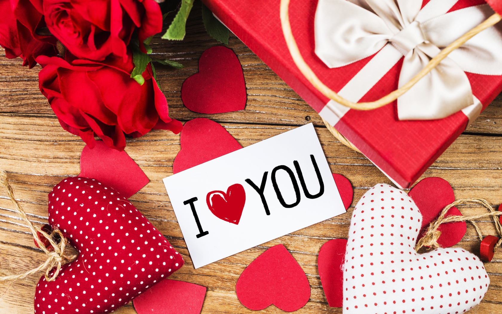 Сердечки, цветы и подарок на столе с запиской