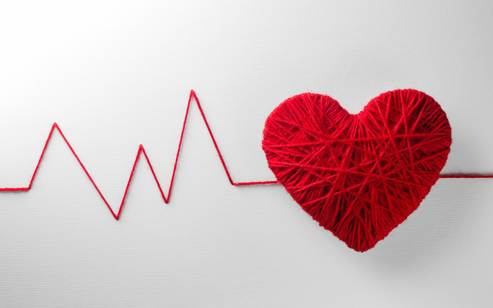 Красное сердце из нитей на сером фоне 