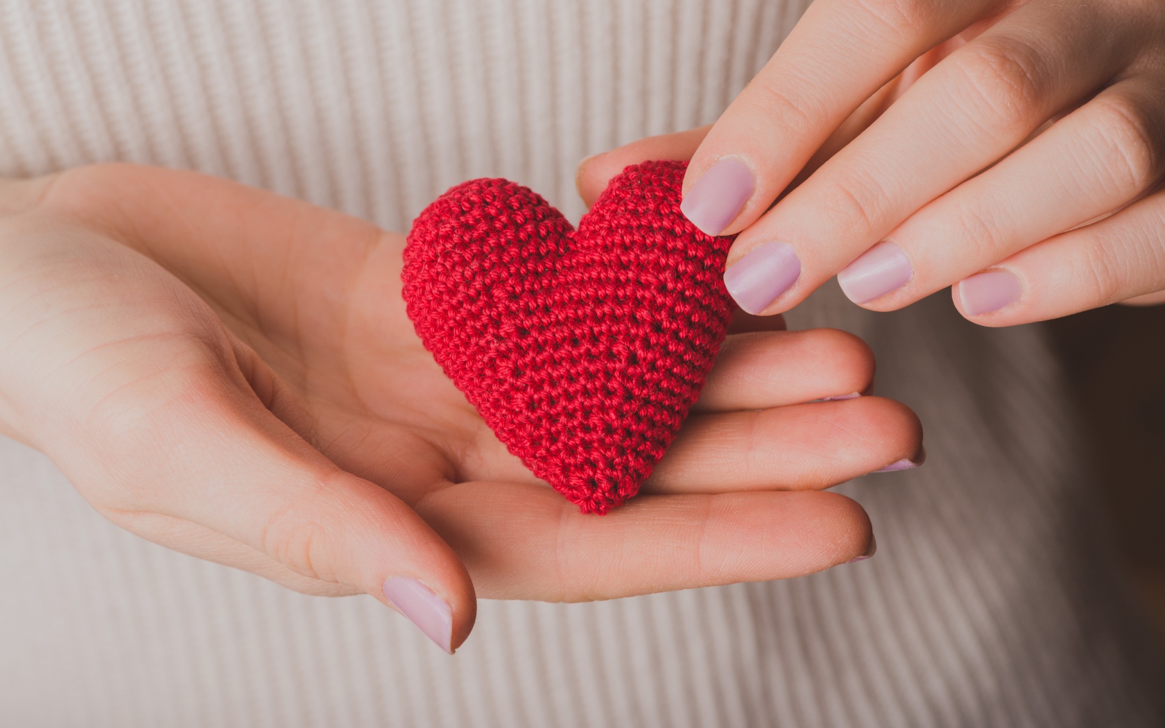Красное вязаное сердце в руках у девушки