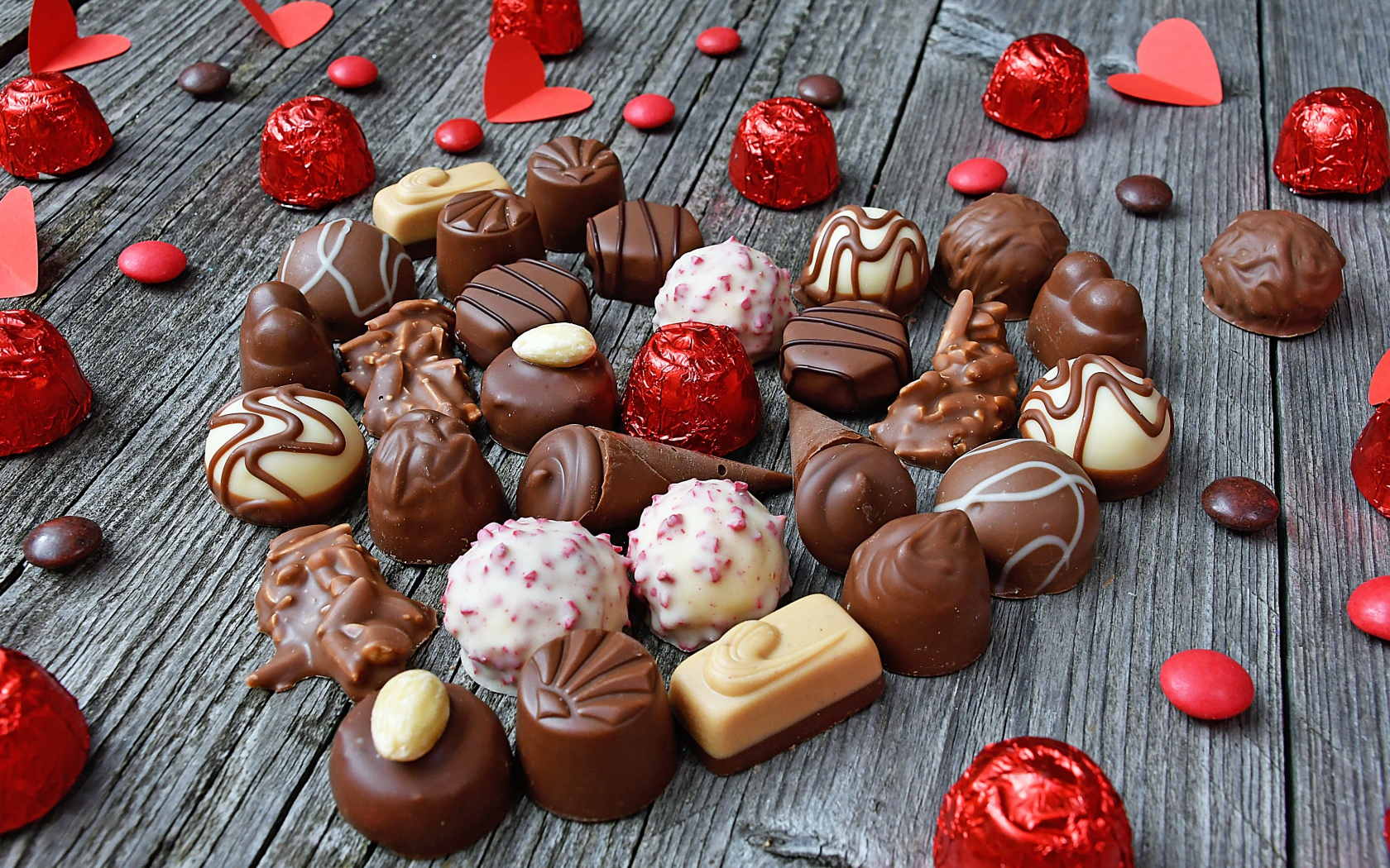 Сладкое сердце из шоколадных конфет на деревянном столе