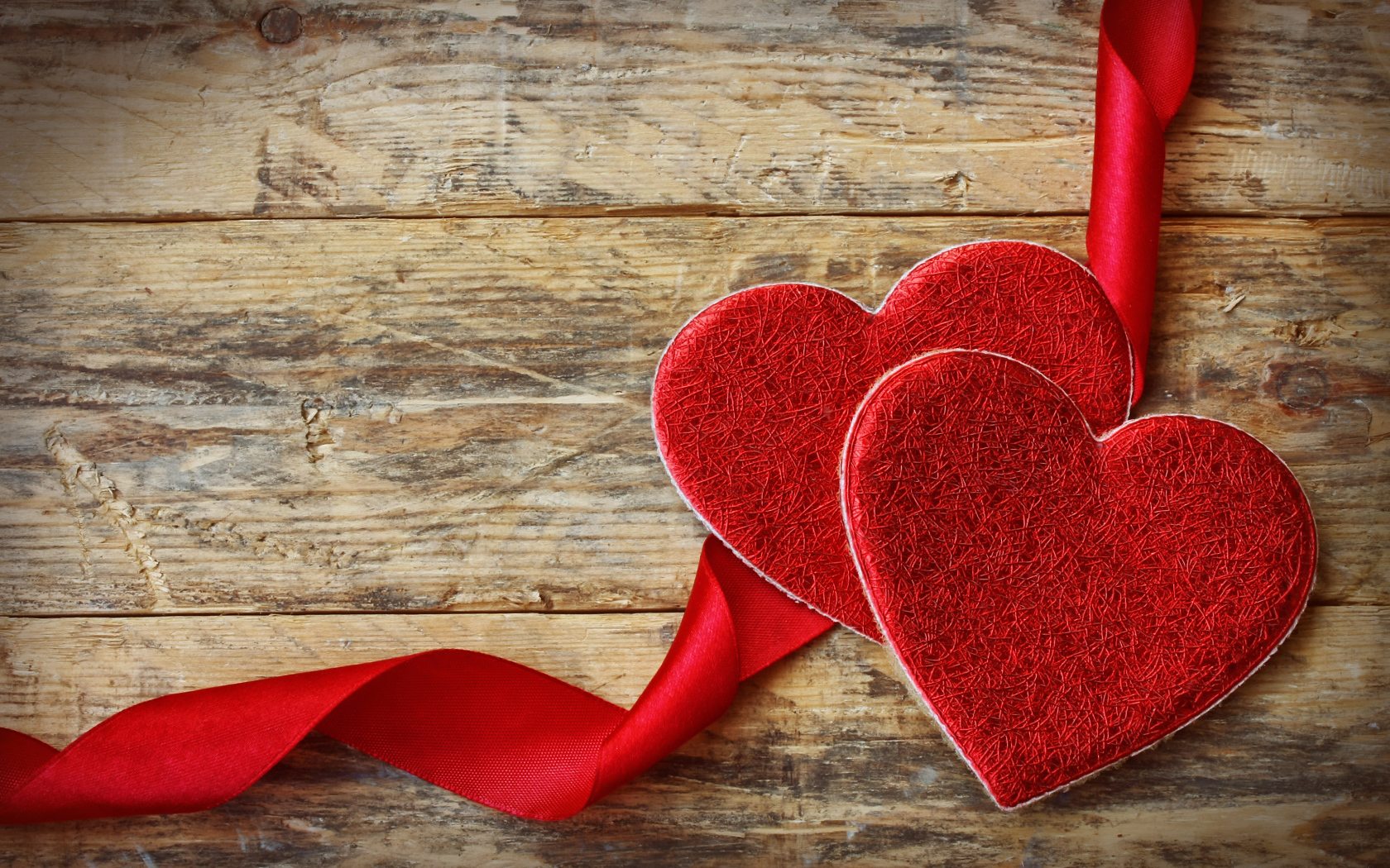 Два сердца с красной лентой на деревянном столе