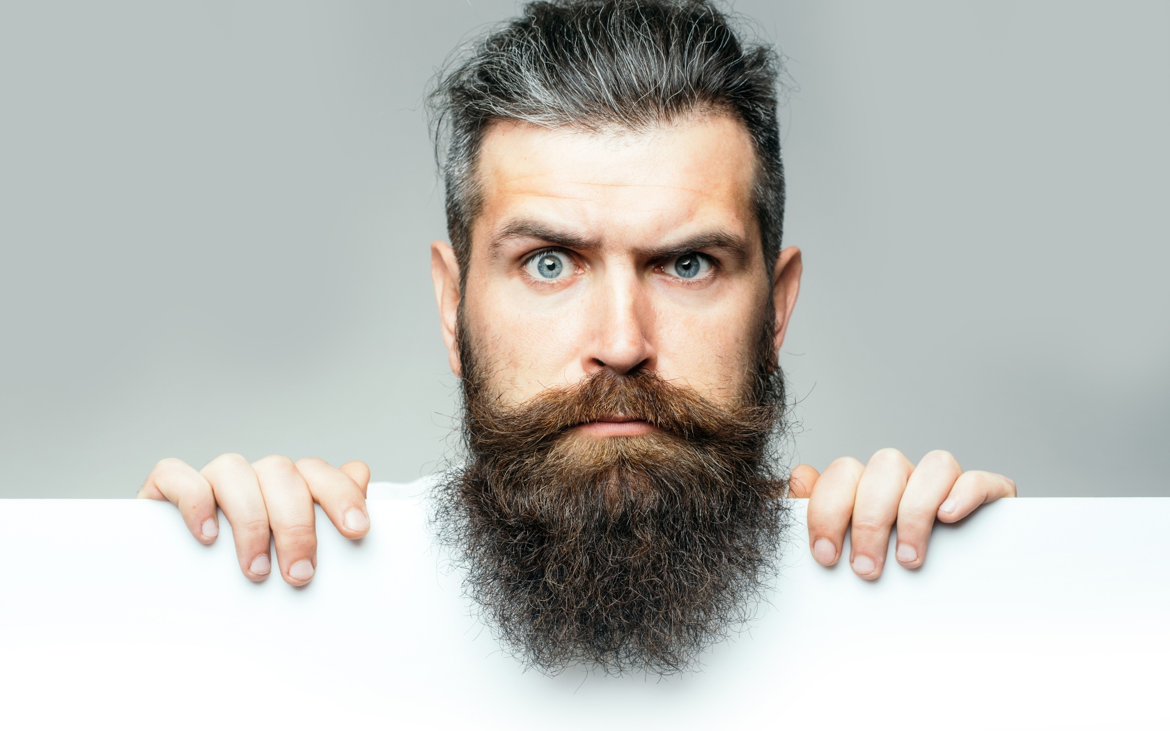 Голубоглазый мужчина с бородой на сером фоне