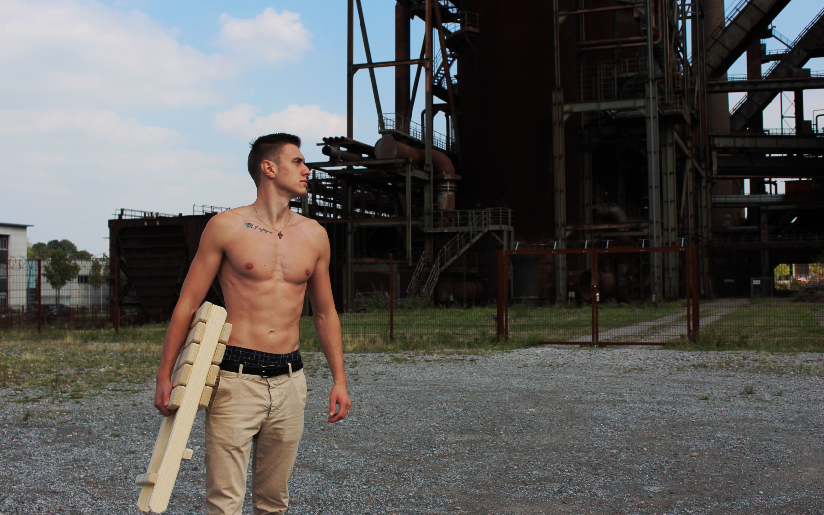 Красивый молодой парень стоит на фоне завода