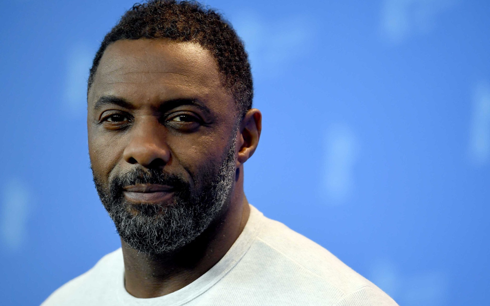 Британский актер Идрис Эльба на голубом фоне