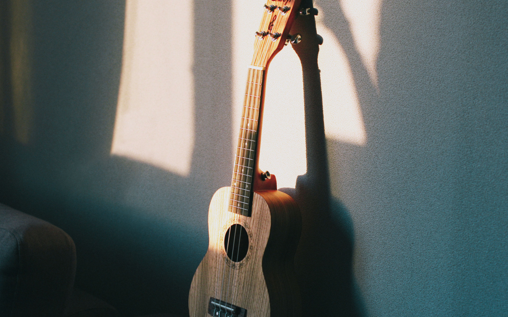 Желтая гитара стоит у серой стены