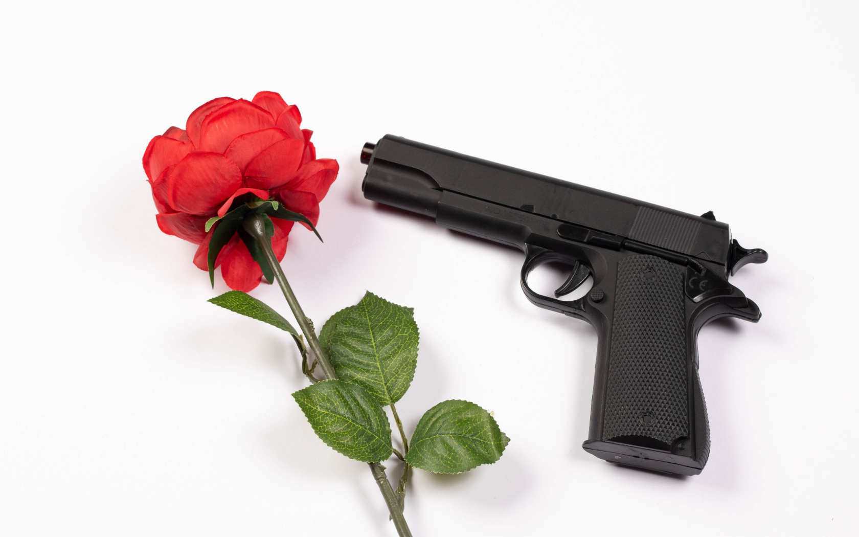 Красная роза и черный пистолет на белом фоне