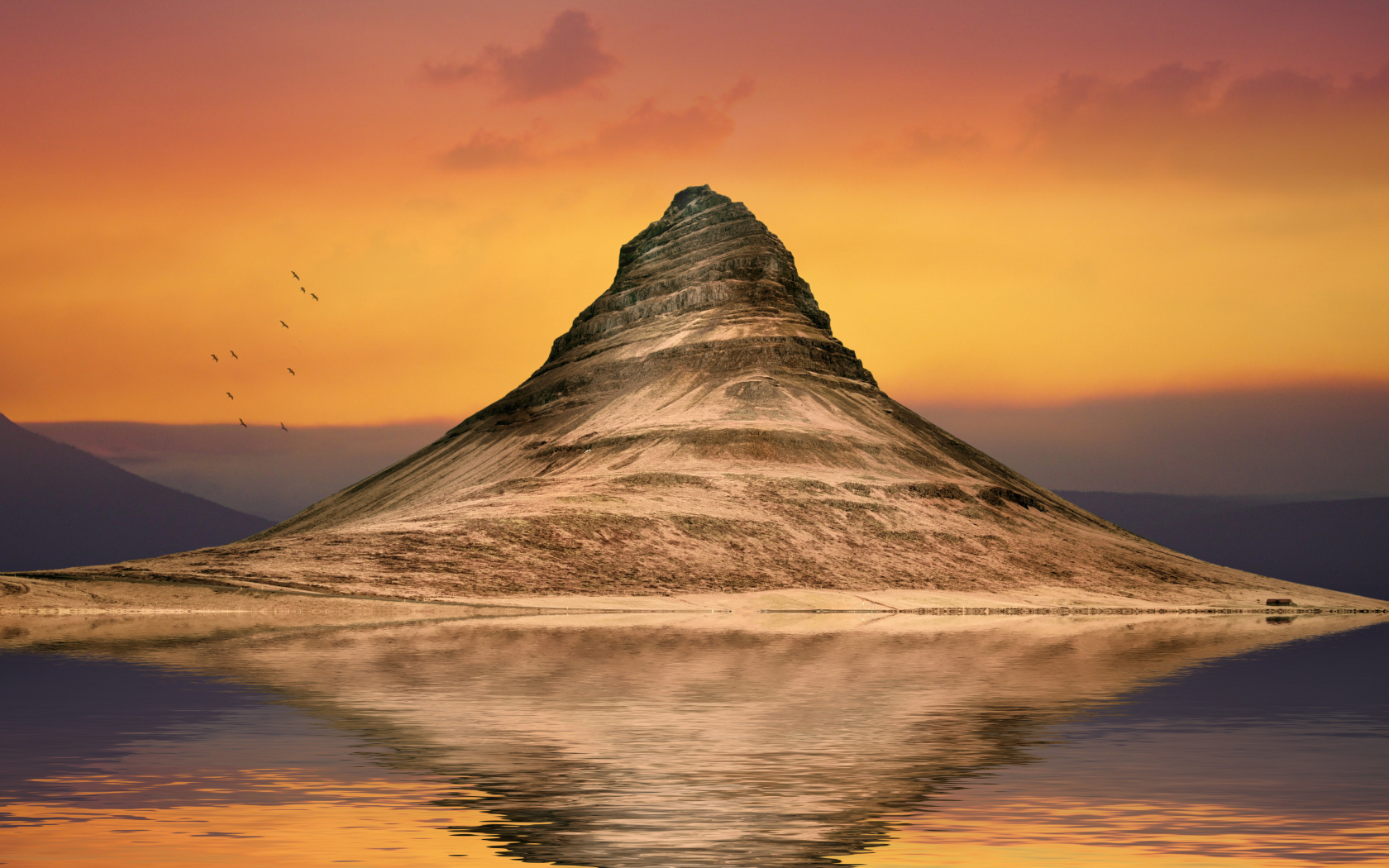 Mountain reflected in the water against the sky at sunset
