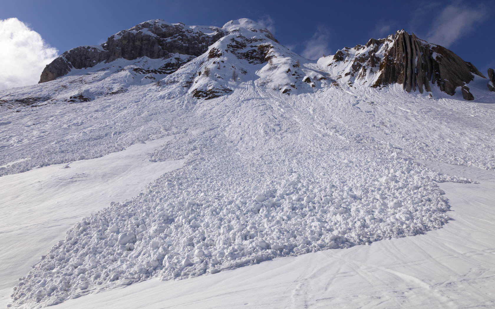 Белая лавина сходит с гор солнечным днем