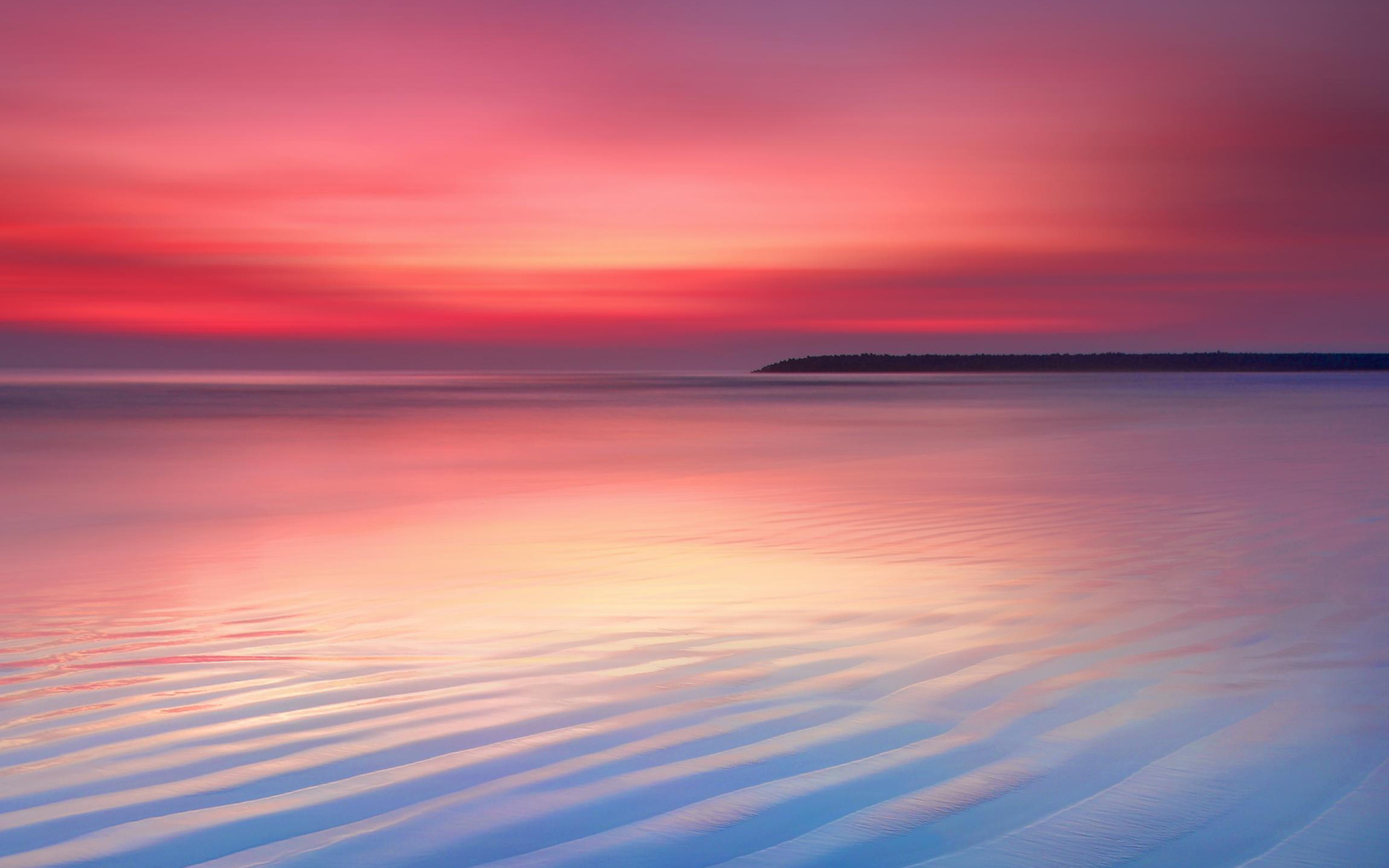 Мокрый белый песок на берегу океана на закате