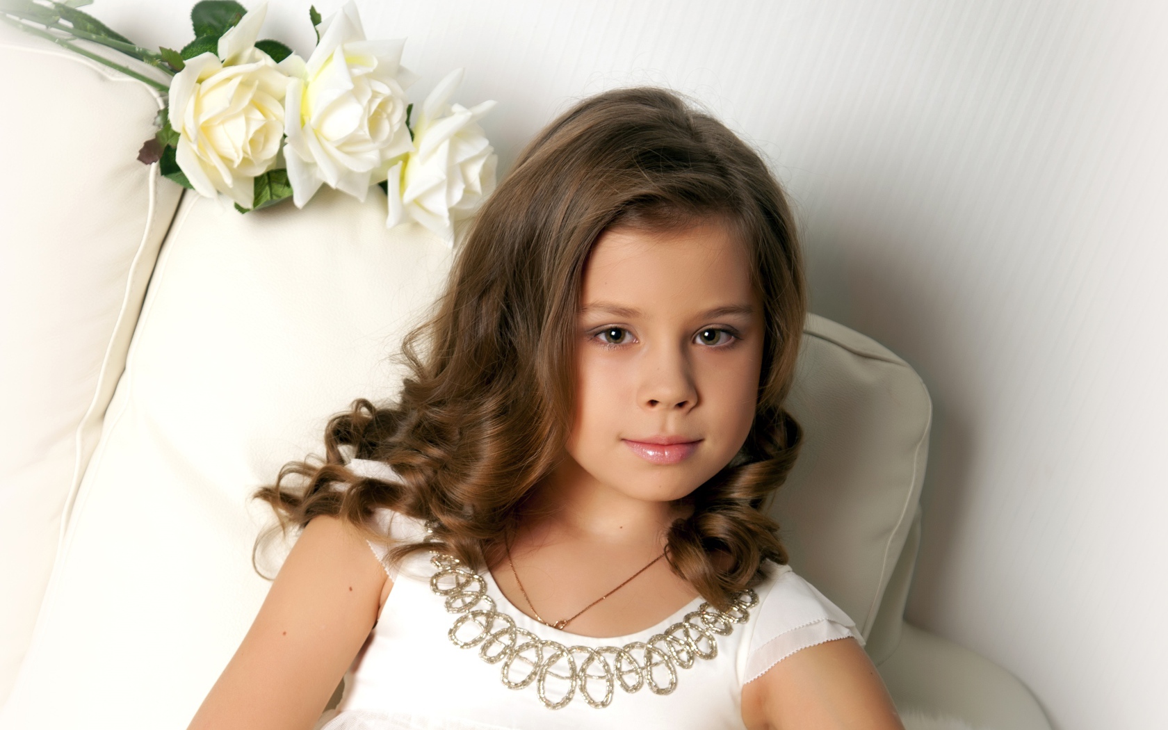 Красивая маленькая девочка сидит в кресле