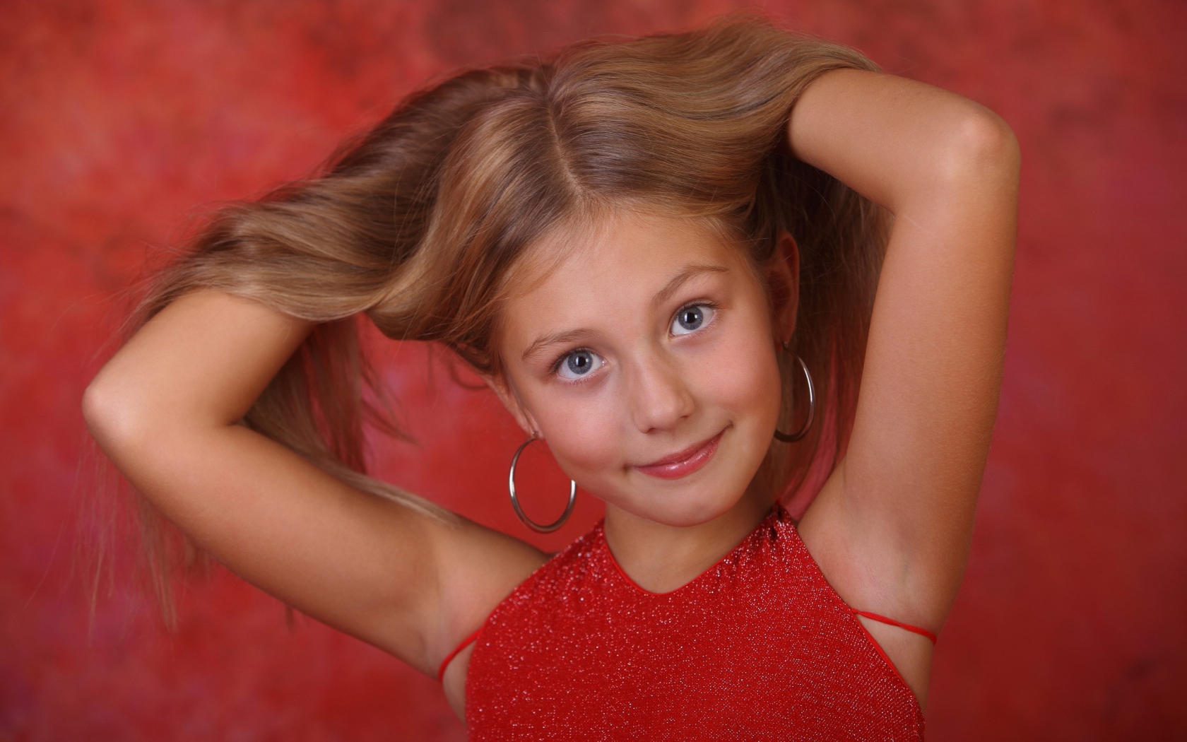 Красивая маленькая девочка с руками в волосах