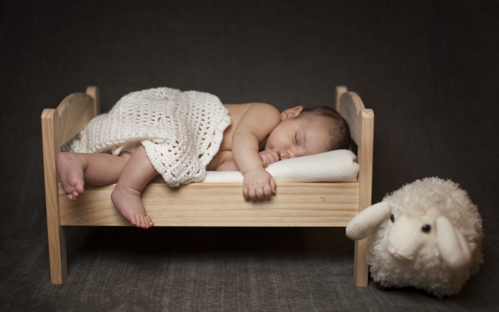 Маленький ребенок спит на деревянной кроватке с игрушкой