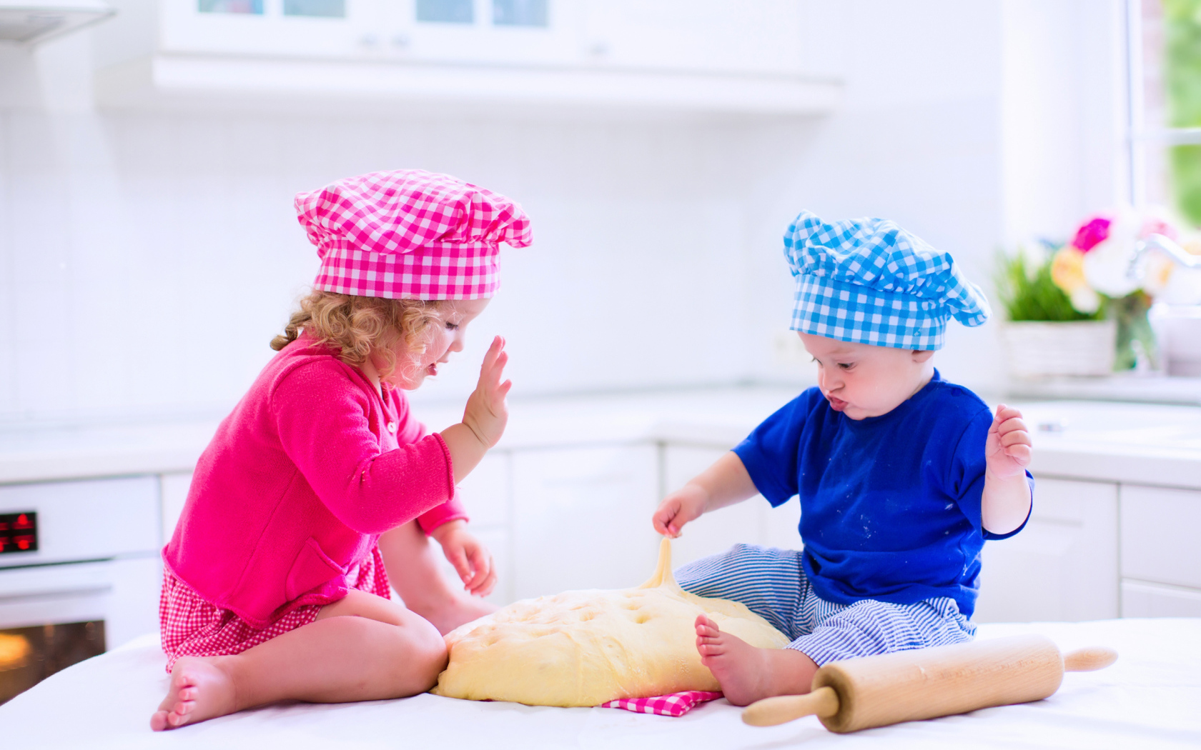 Маленькие мальчик и девочка на кухне с тестом