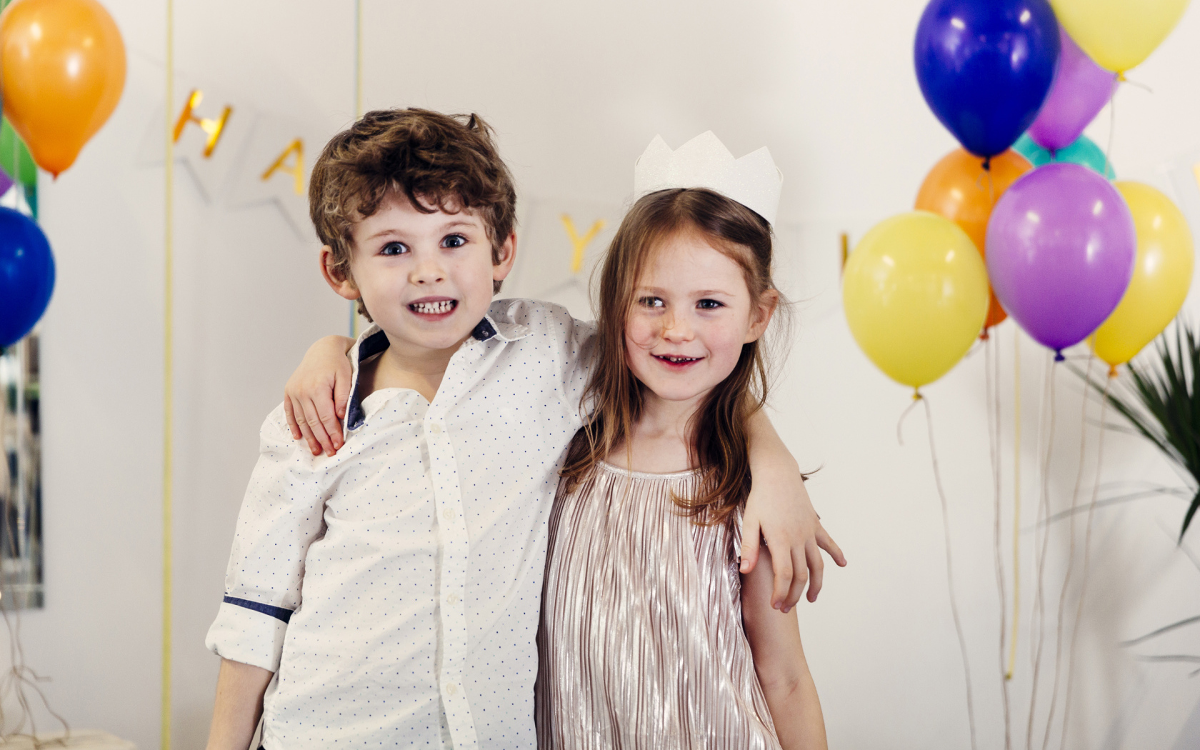 Маленькие мальчик и девочка на празднике с воздушными шарами