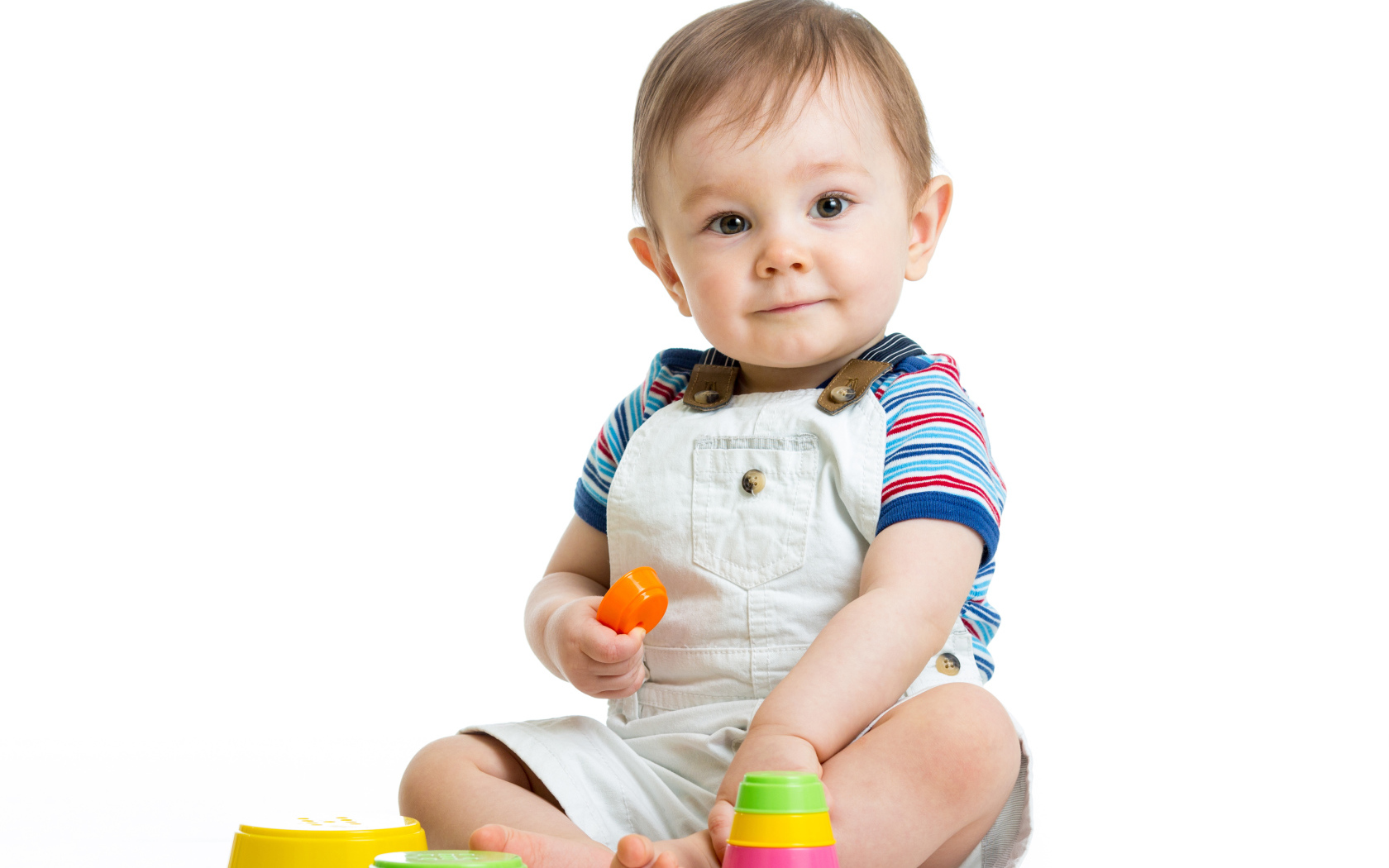 Маленький мальчик играет с пирамидкой на белом фоне