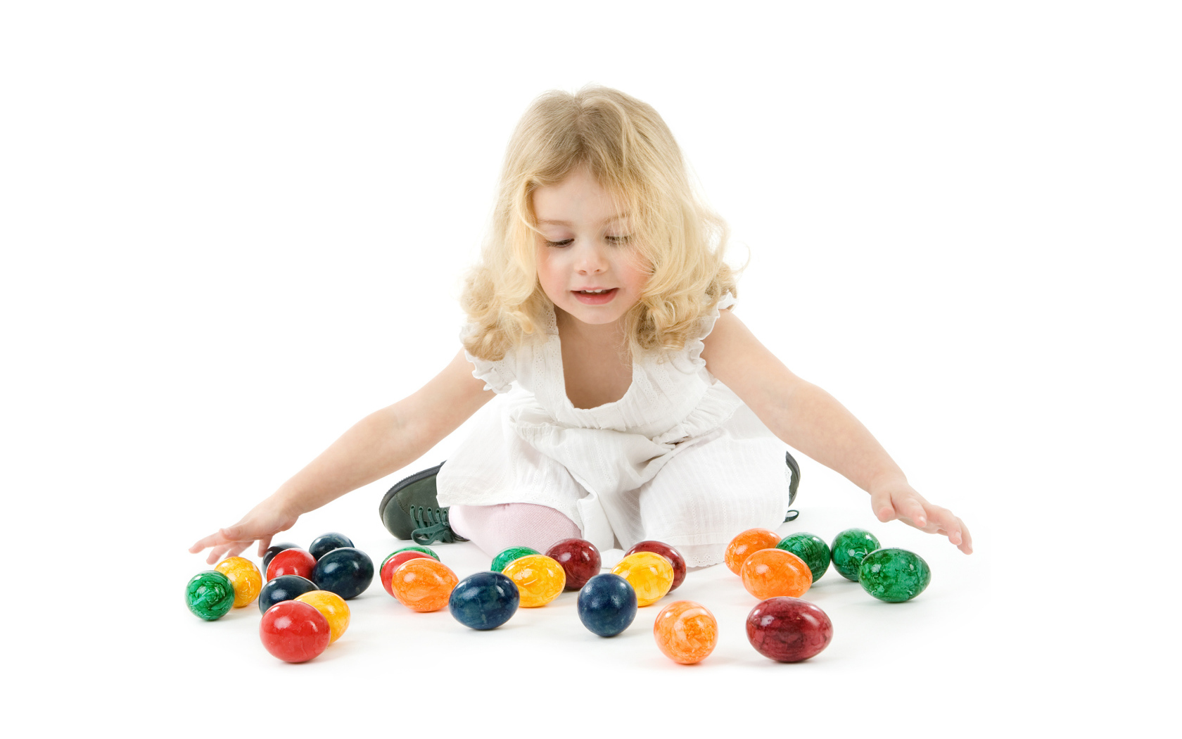 Маленькая девочка блондинка с крашеными яйцами на белом фоне