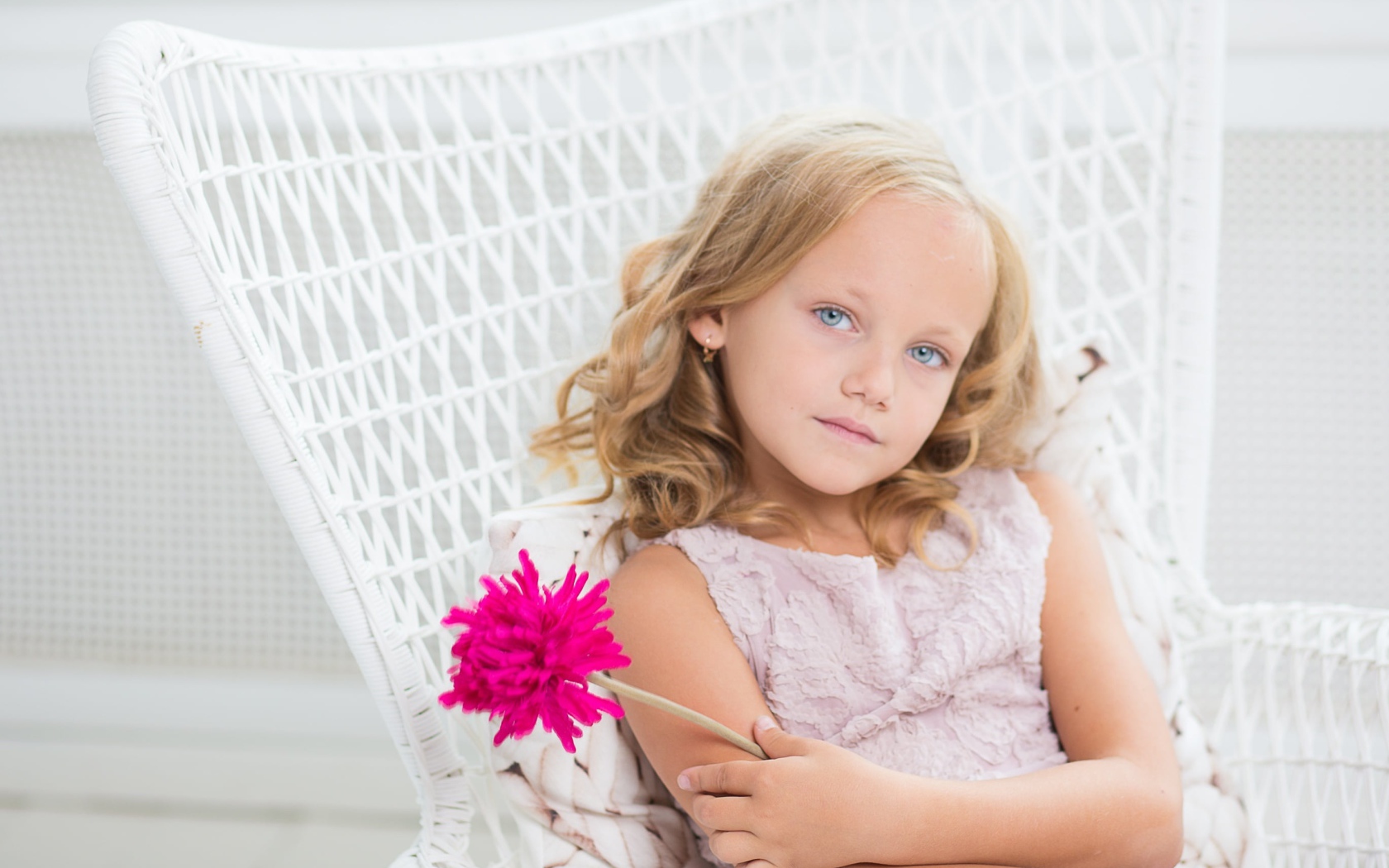 Маленькая девочка сидит в белом кресле с розовым цветком