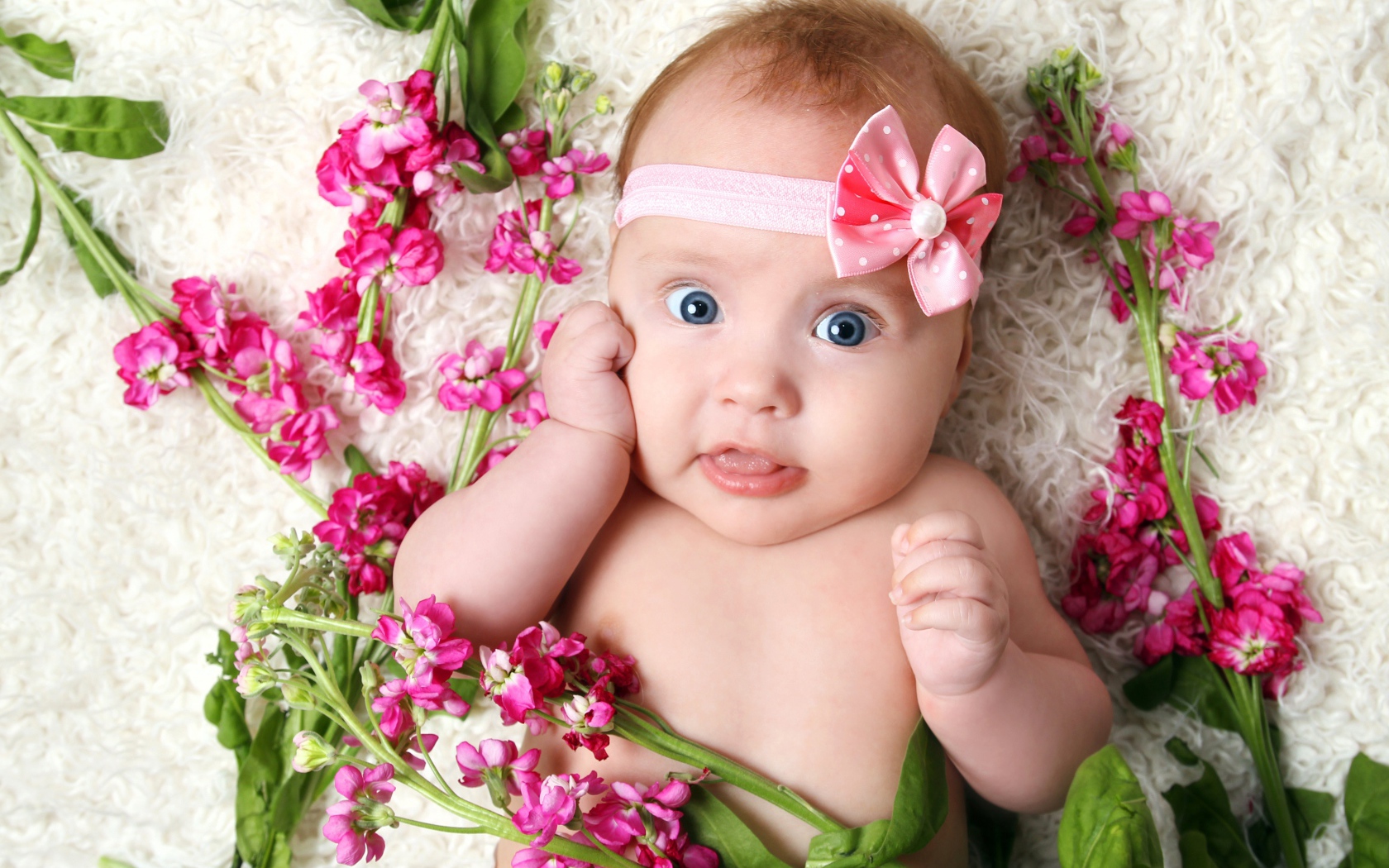 Маленькая девочка с повязкой лежит с розовыми цветами