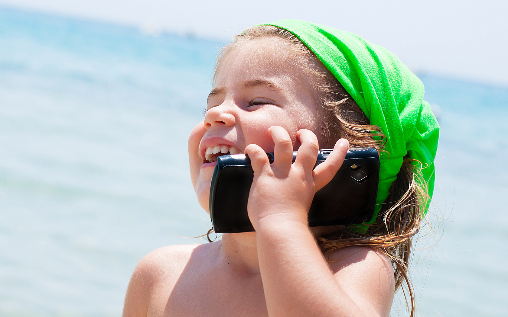 Маленькая девочка с телефоном на пляже