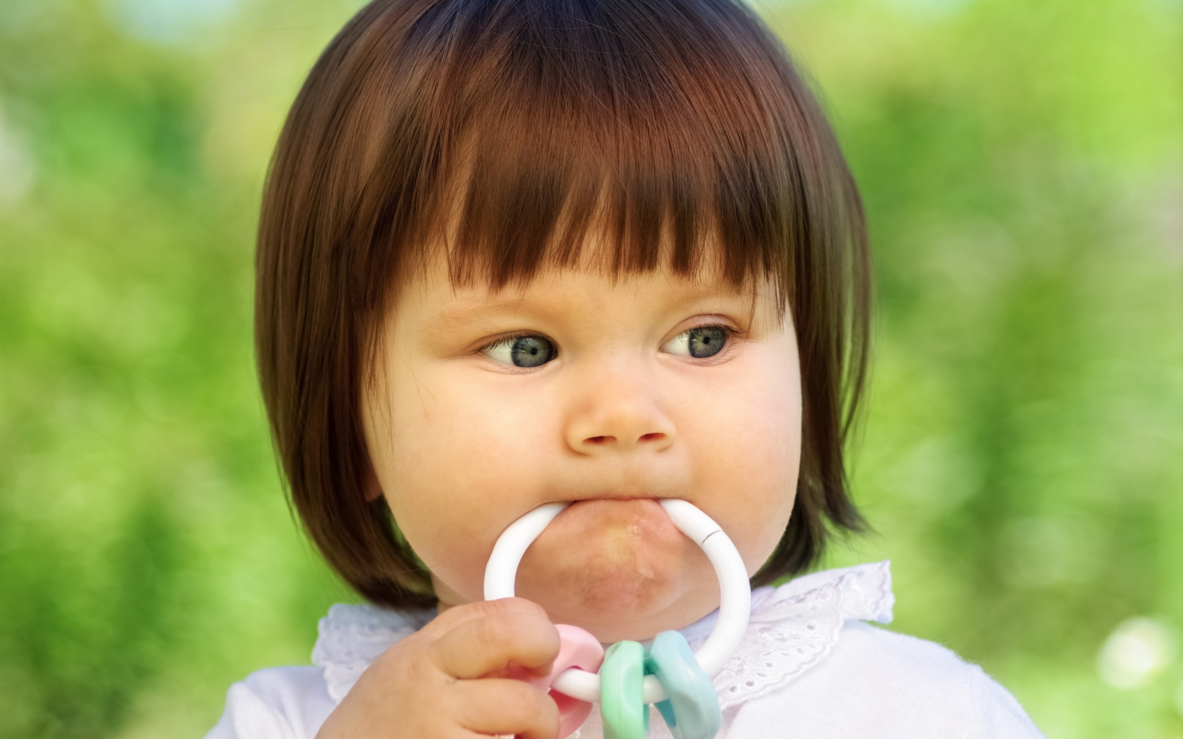 Маленькая девочка с погремушкой во рту