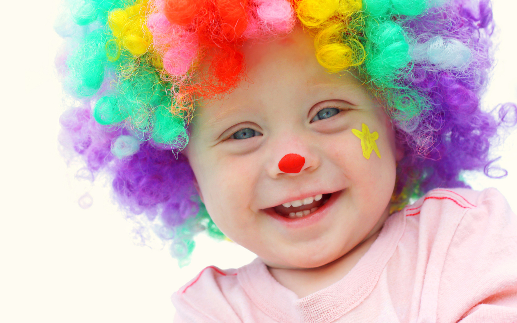 Маленький улыбающийся мальчик в костюме клоуна на белом фоне