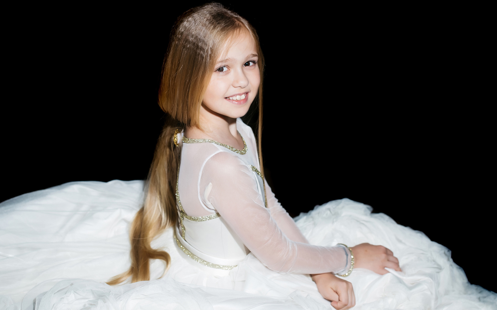 Smiling girl in a beautiful white dress on a black background