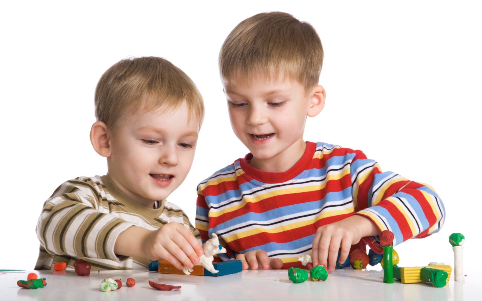 Два мальчика играют в игрушки на белом фоне
