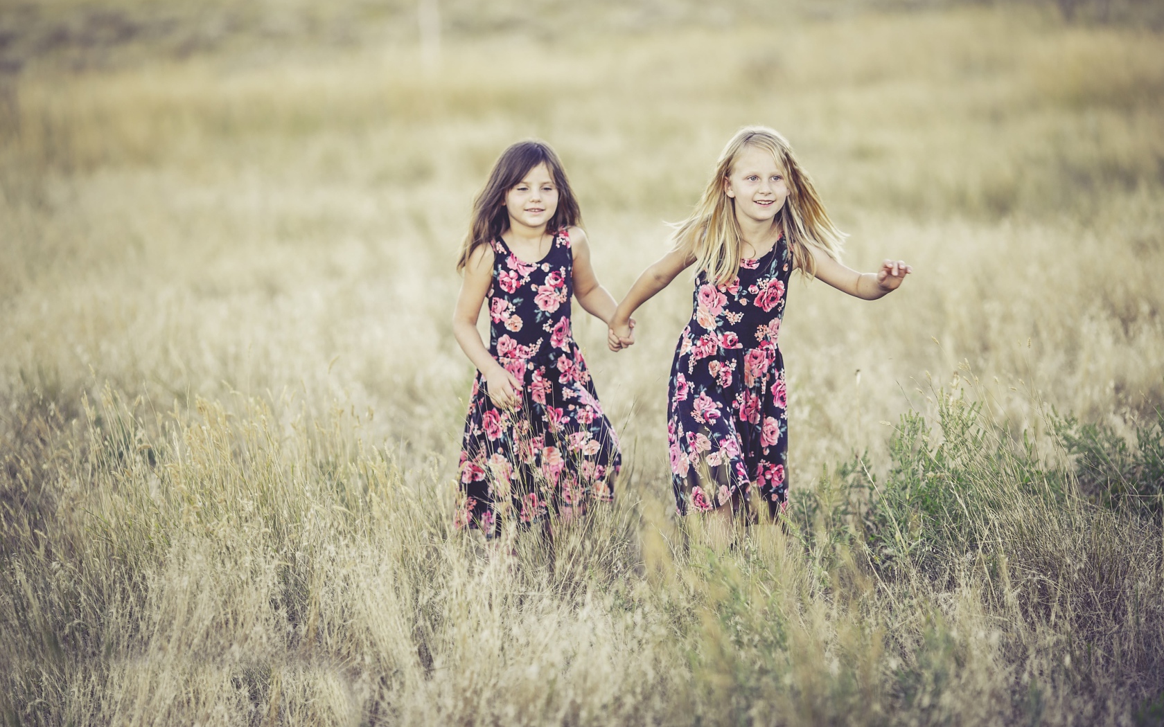 Две маленькие девочки бегут по траве