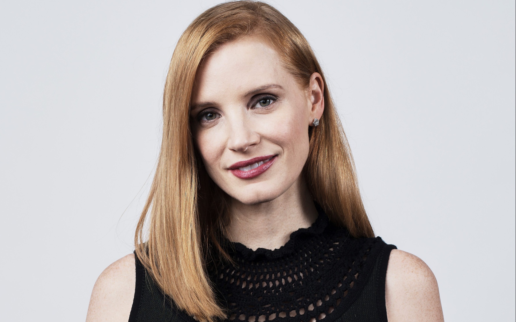 Красивая рыжеволосая актриса Джессика Честейн на сером фоне