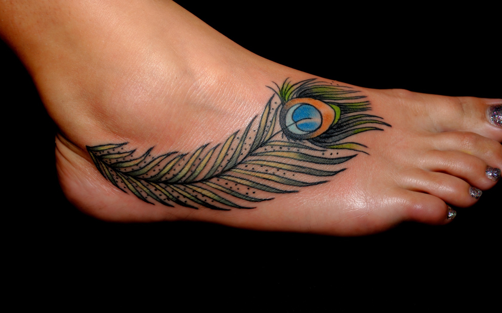 Татуировка перо павлина на ноге на черном фоне