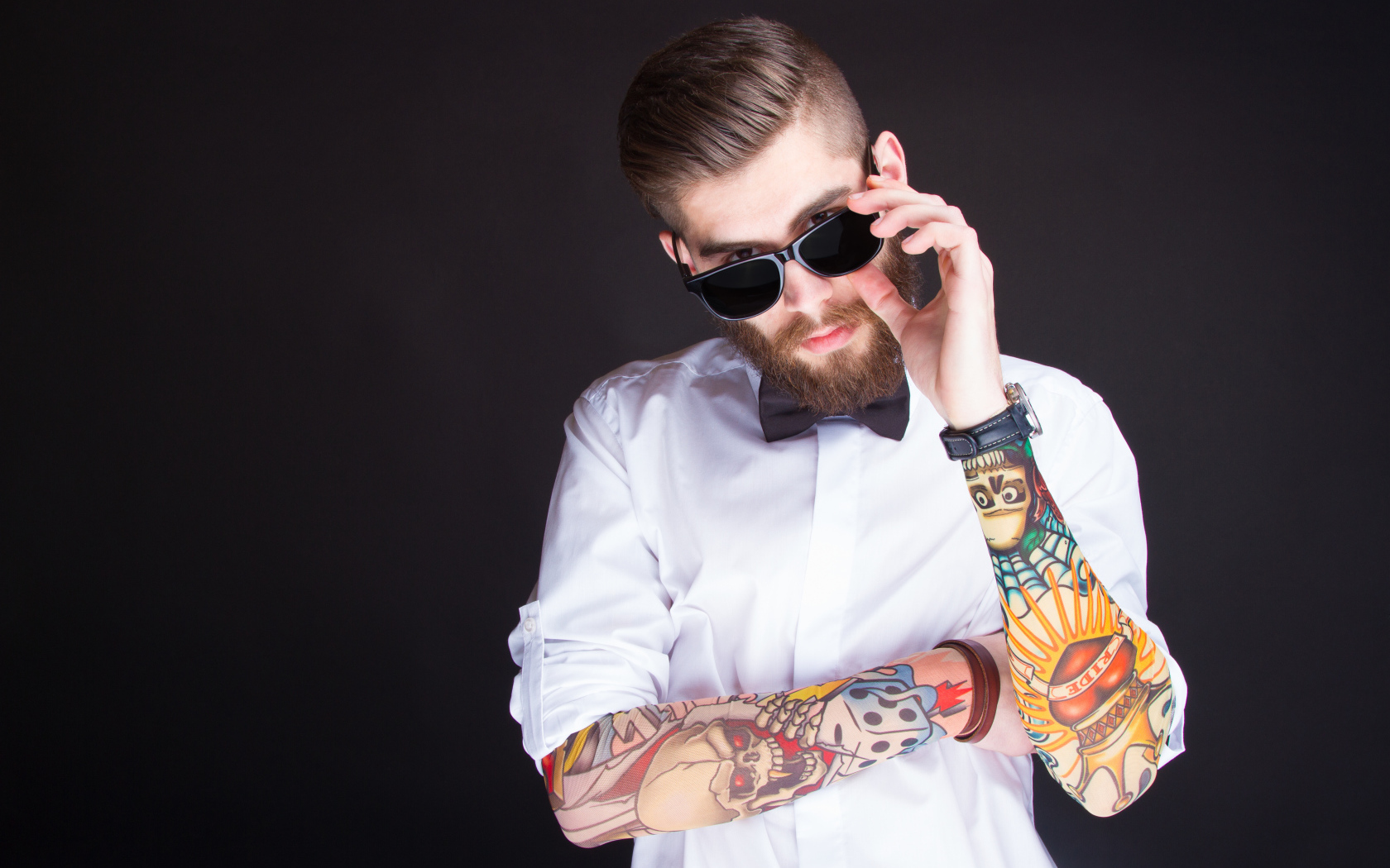 Мужчина в очках с татуировками на руках на сером фоне