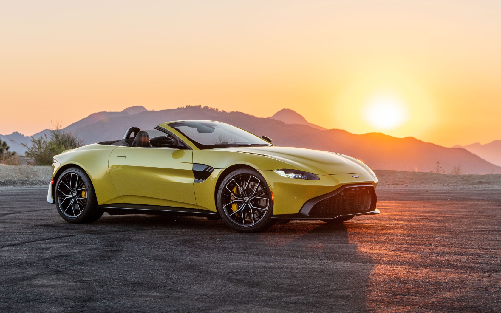 Желтый автомобиль  Aston Martin Vantage Roadster, 2021 года на закате