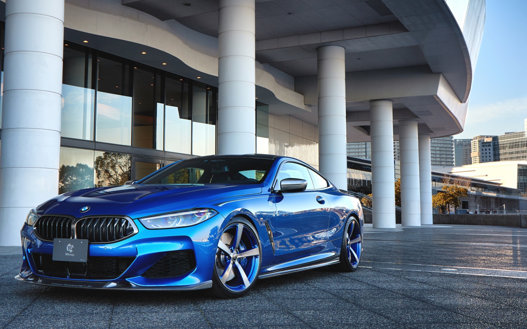 Синий автомобиль BMW M850i XDrive Coupe 2020 года у здания 