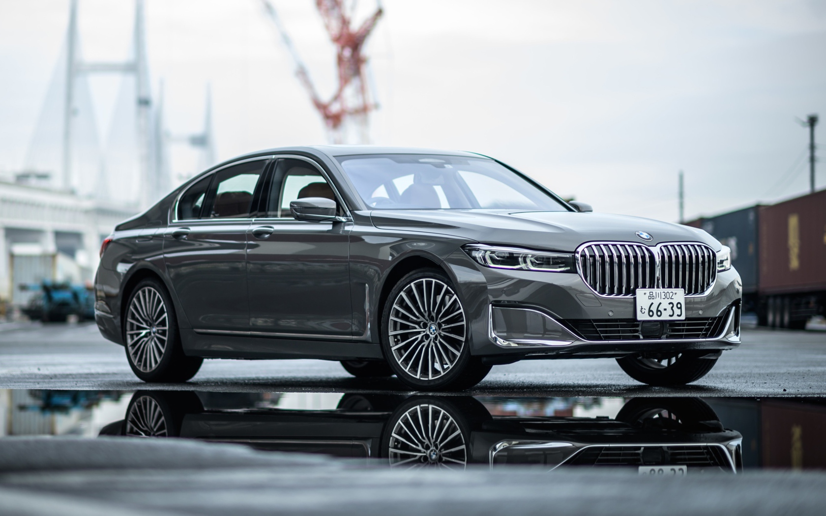 Серебристый автомобиль BMW 745e на мокром асфальте 