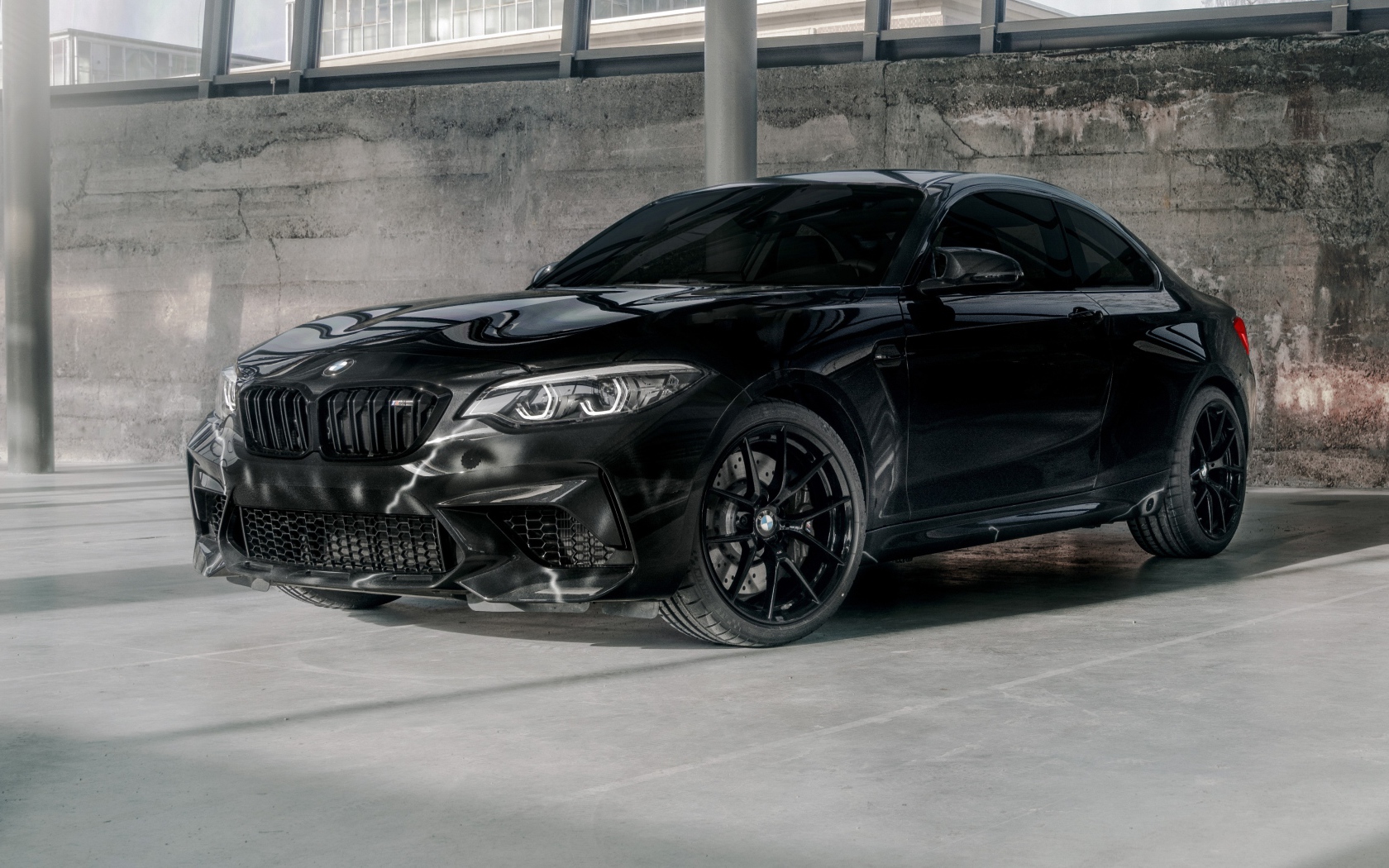 Черный автомобиль  BMW M2, 2020 года у бетонной стены