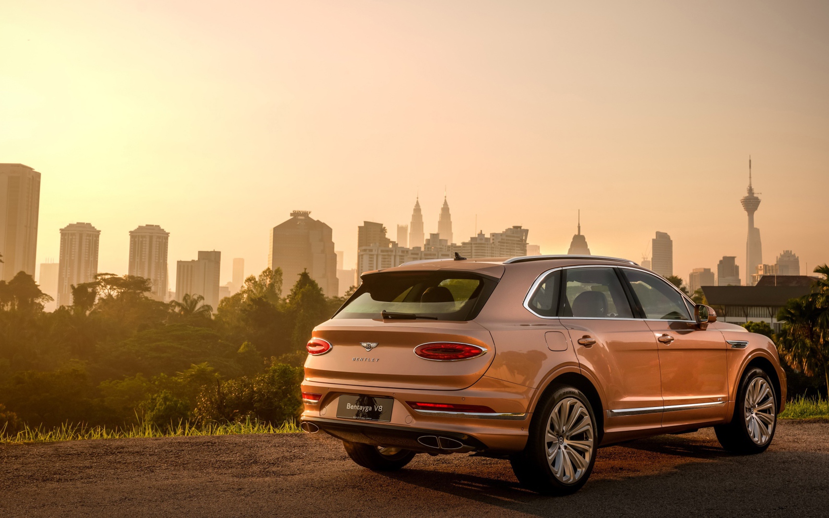 Автомобиль Bentley Bentayga V8 2020 года вид сзади на фоне города 