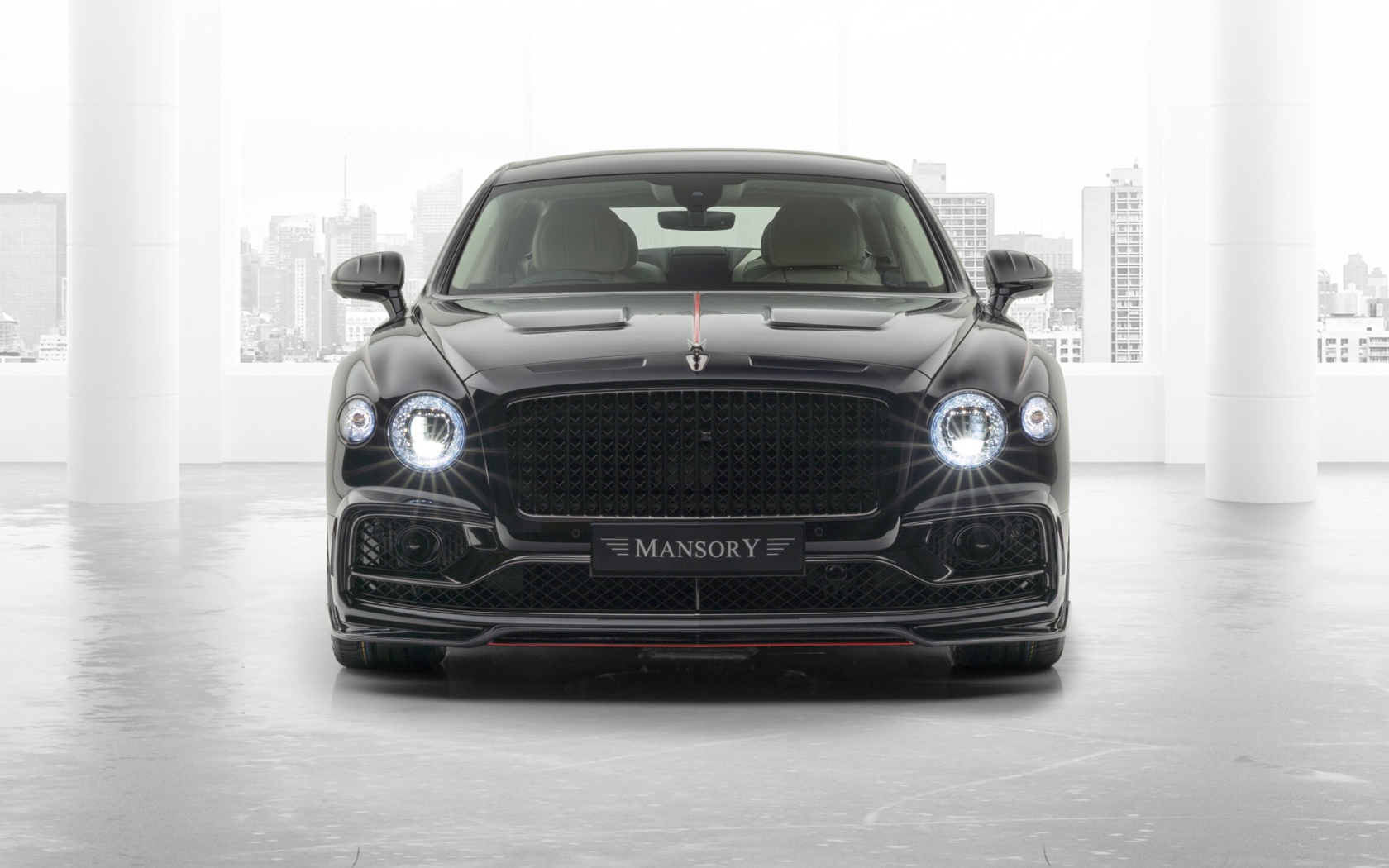 Черный автомобиль Mansory Bentley Flying Spur 2020 года с включенными фарами 