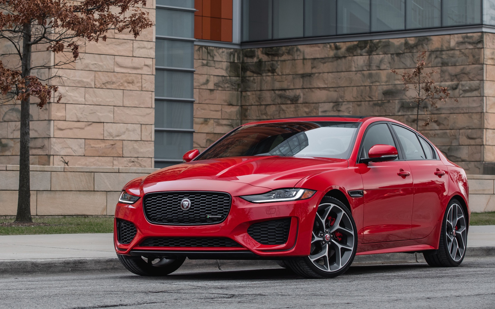 Красный автомобиль Jaguar XE P300 R-Dynamic, 2020 года у здания