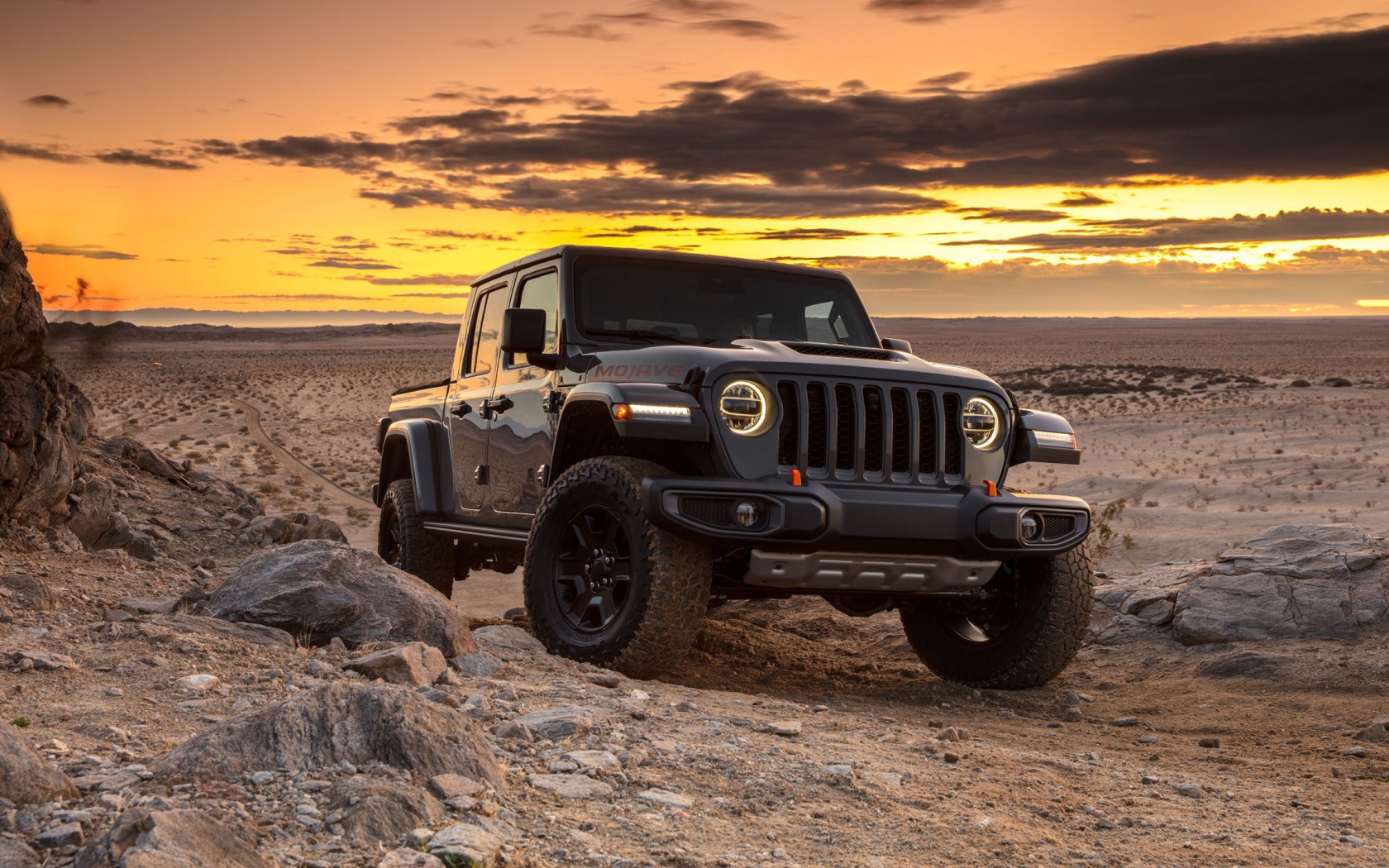 Черный внедорожник Jeep Gladiator Mojave, 2020 года в пустыне на закате