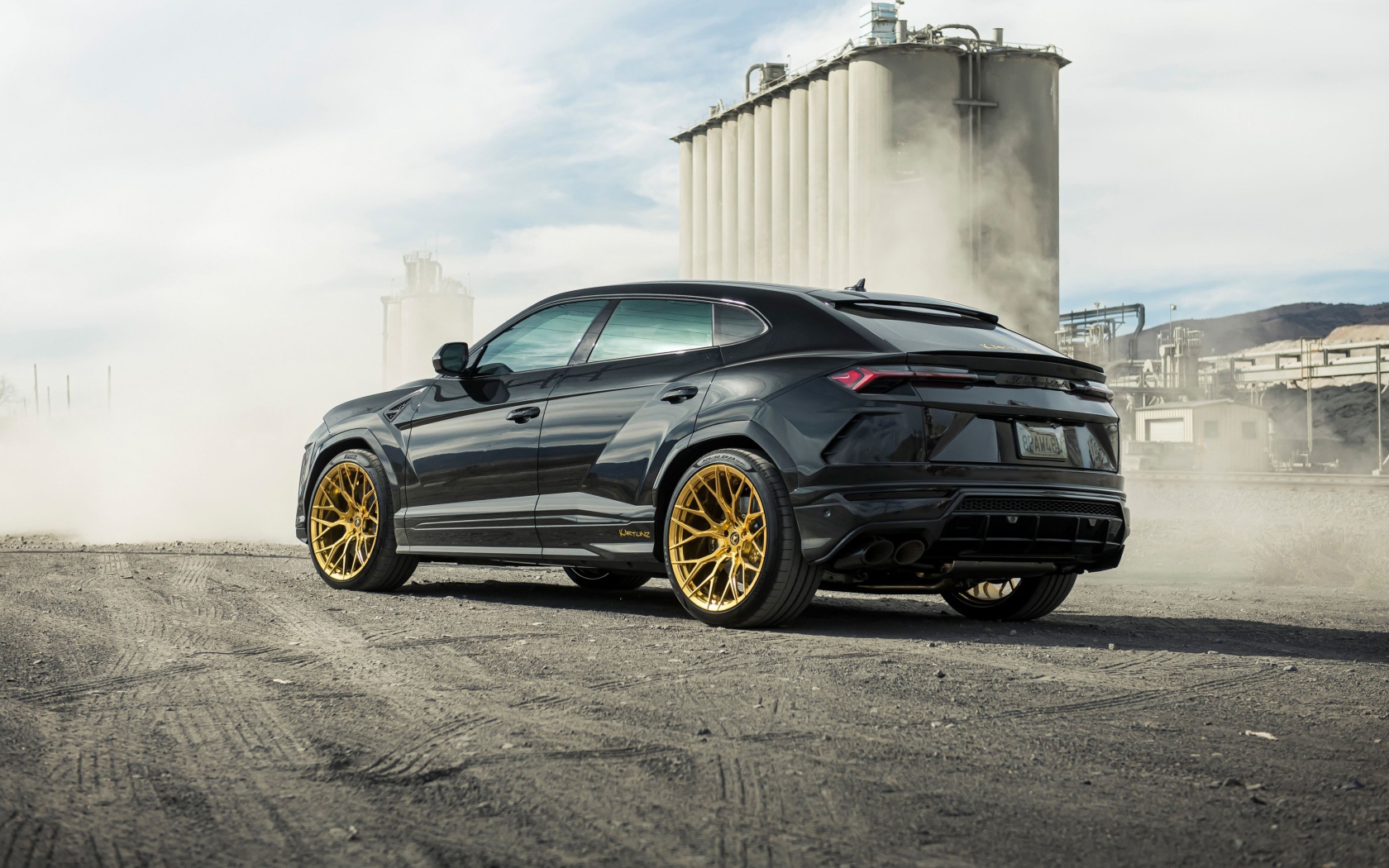 Черный внедорожник  Lamborghini Urus 2020 года на фоне завода вид сзади