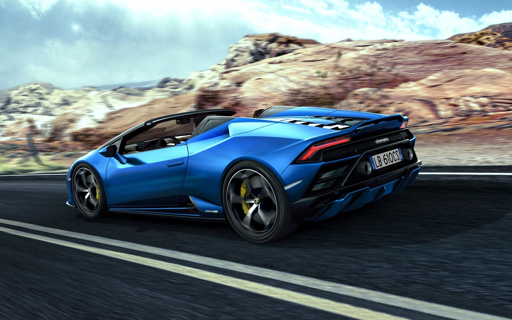 Быстрый синий автомобиль Lamborghini Huracan EVO RWD Spyder 2020 года на фоне скал 