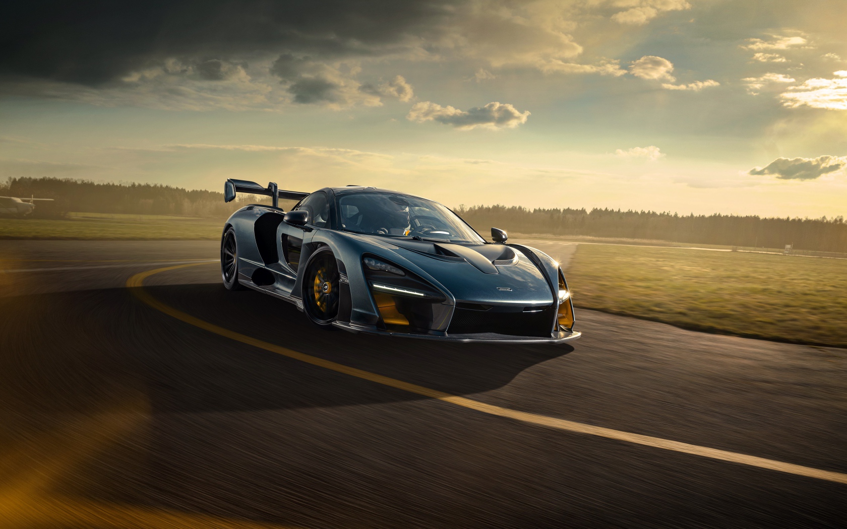 Гоночный автомобиль  McLaren Senna 2020 года на фоне заката 