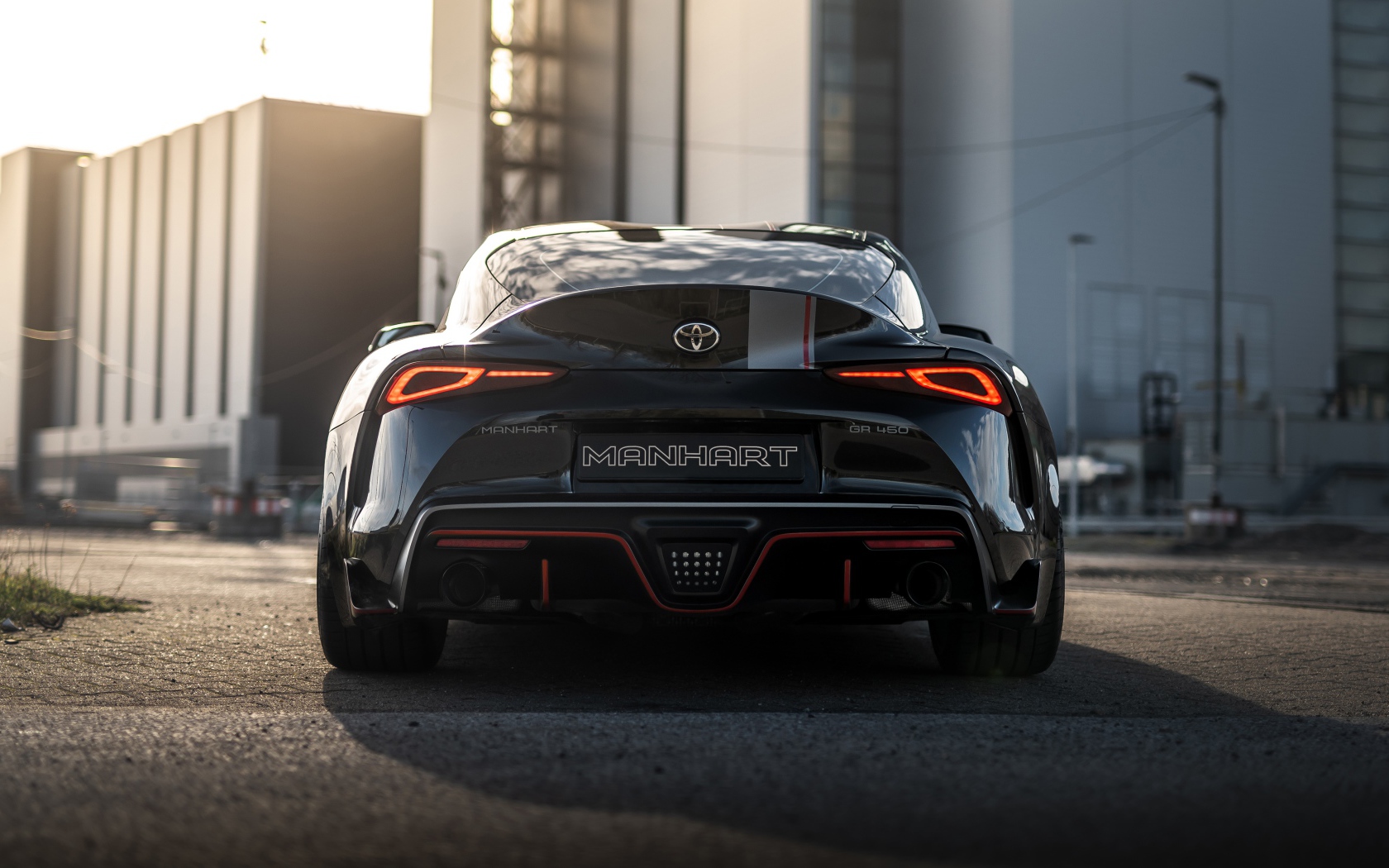 Черный автомобиль Manhart Supra GR 450 2020 года у домов