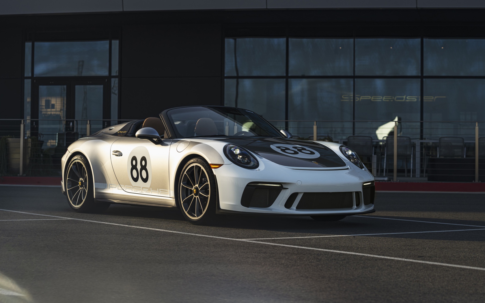 Спортивный автомобиль Porsche 911, 2019 года у стеклянного здания