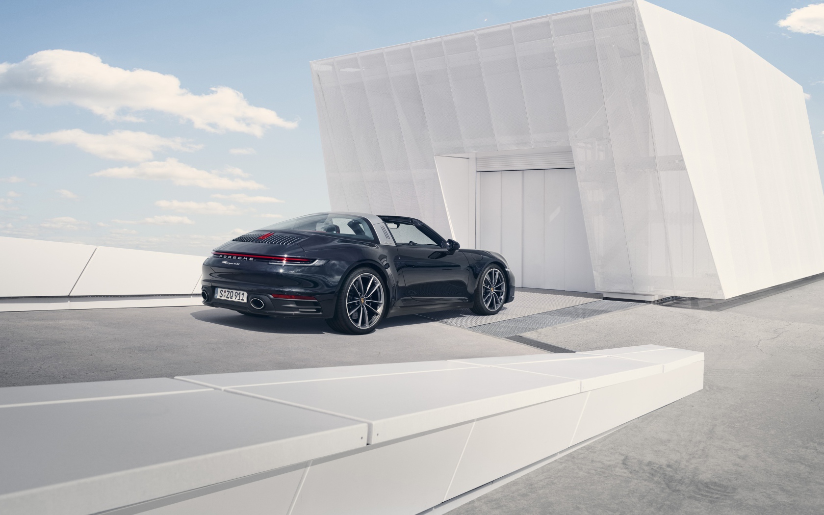 Черный автомобиль Porsche 911 Targa 4S 2020 года у гаража 
